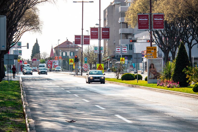 Трехполосная улица в центре города Сплит, Хорватия. Мимо проезжают машины, bmw 1-й серии в фокусе. Птица на дороге, . Реклама на столбах роялти бесплатно стоковые фотографии