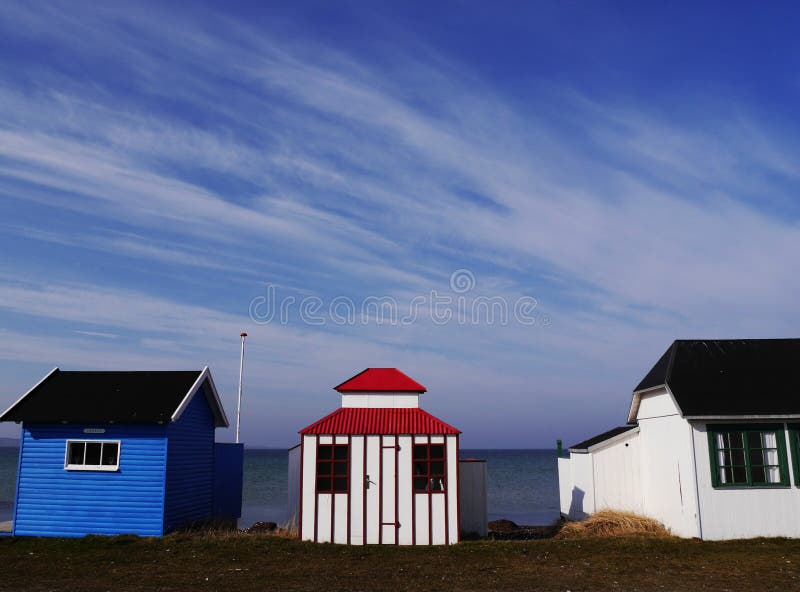 Three little brightly-painted wooden beach huts, Aero Island, Denmark