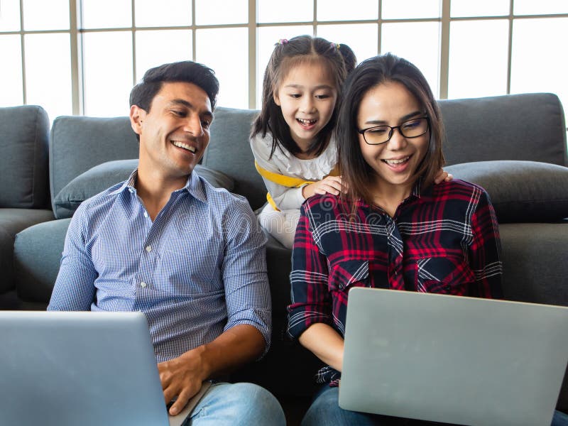 Three member of family working together. Three members of diverse family, Caucasian father and Asian mother and little half daughter sitting together in house