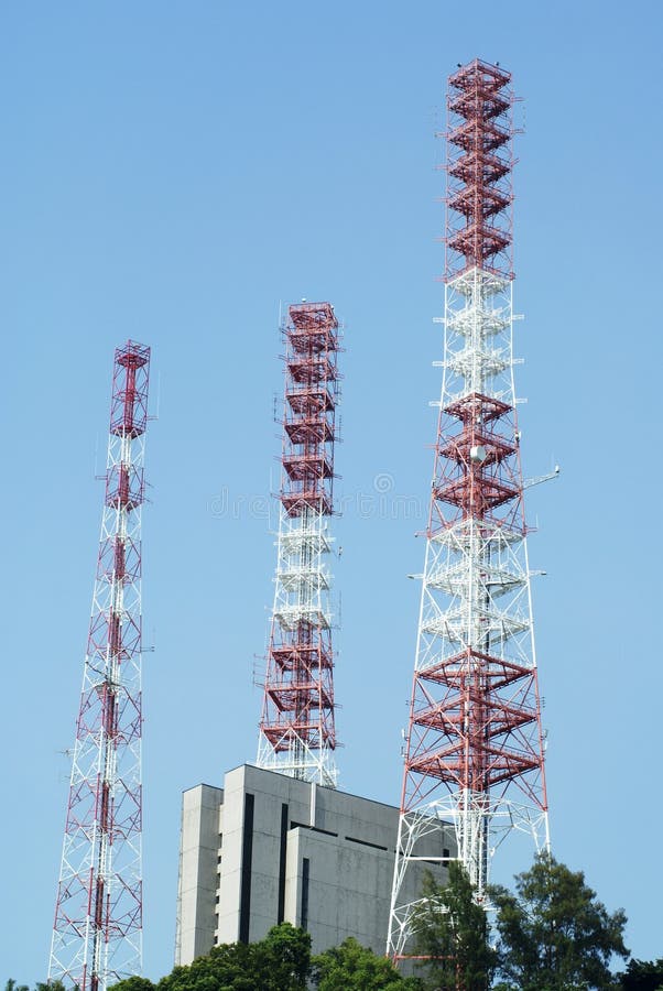 Three telecoms towers on top of a hill with a building between them. Three telecoms towers on top of a hill with a building between them.