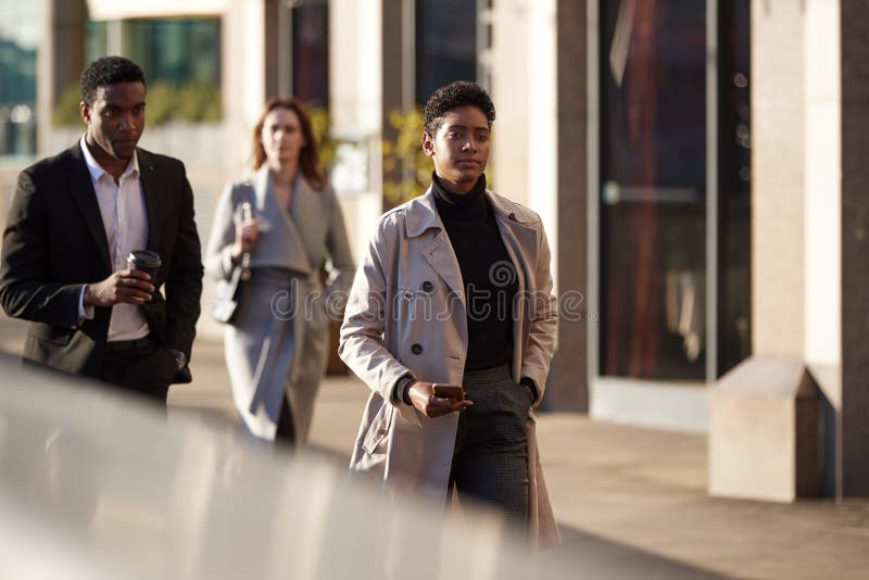 Three millennial city workers walking in a London street, selective focus stock photo Three millennial city workers walking in a London street, selective focus stock photo