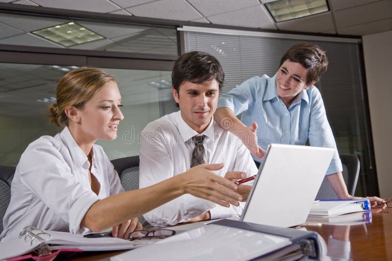 Tre impiegati nella sala riunioni, a lavorare insieme su documenti e pc portatile.