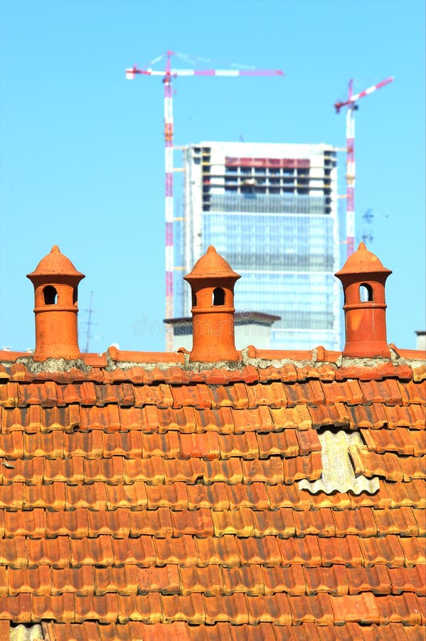 Three old chimney pot with modern construction in the background