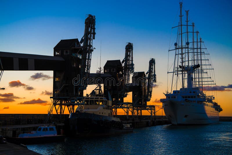 Old sailer five-master sailer in front of three old cranes in evening backlight with great evening skies, Barbados, Carribean Sea