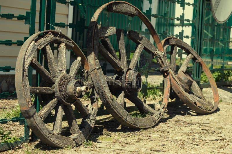 Three old wagon wheel standing at the fence stock photo Three old wagon wheel standing at the fence stock photo