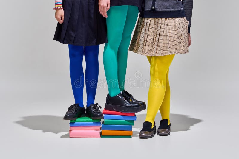 Three people in colorful tights stand atop stack of books, symbolizing collaborative learning and bright start to royalty free stock photography