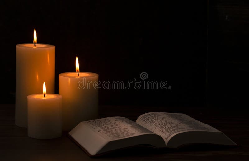 Three Pillar Candles Burning in a Dark Room with a Bible Stock Image