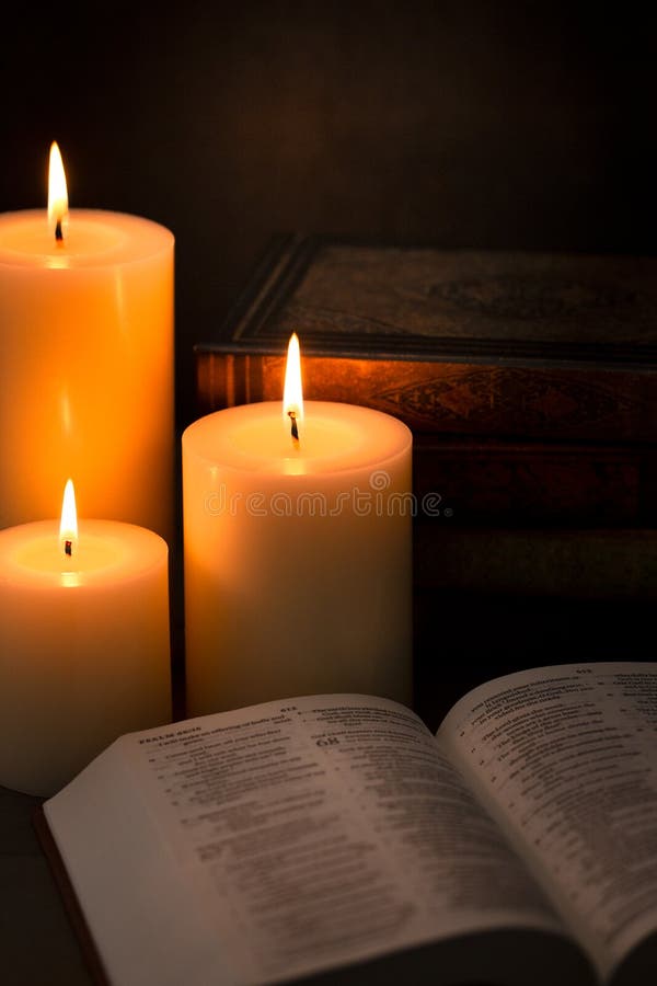 Three Pillar Candles Burning in a Dark Room with a Bible Stock Image