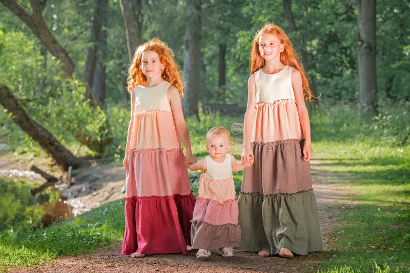 Three Red-haired Sisters in Long Linen Dresses Blow Bubbles in the Park ...