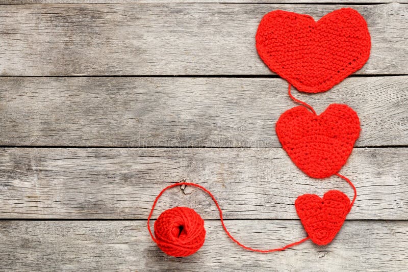 Three red knitted hearts on a gray wooden background, symbolizing love and family. Family relationship, bonds royalty free stock photography Three red knitted hearts on a gray wooden background, symbolizing love and family. Family relationship, bonds royalty free stock photography