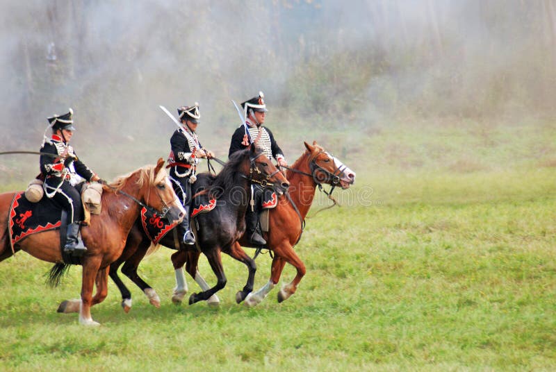 Three reenactors dressed as Napoleonic war soldiers ride horses royalty free stock images