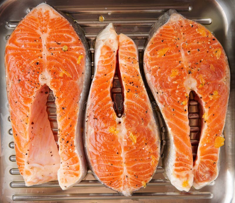 Three salmon steaks prepared for frying on grill pan