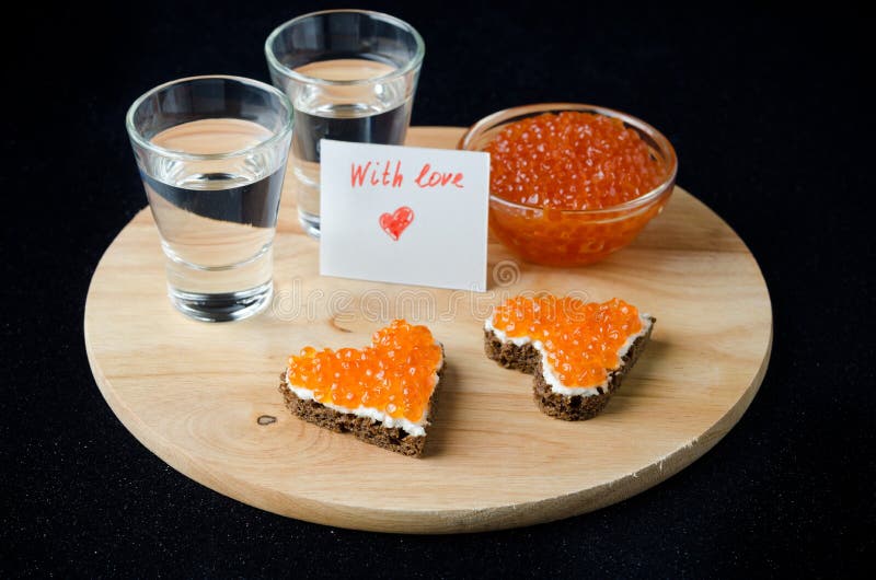 Three sandwich with red caviar in the form of a heart, vodka