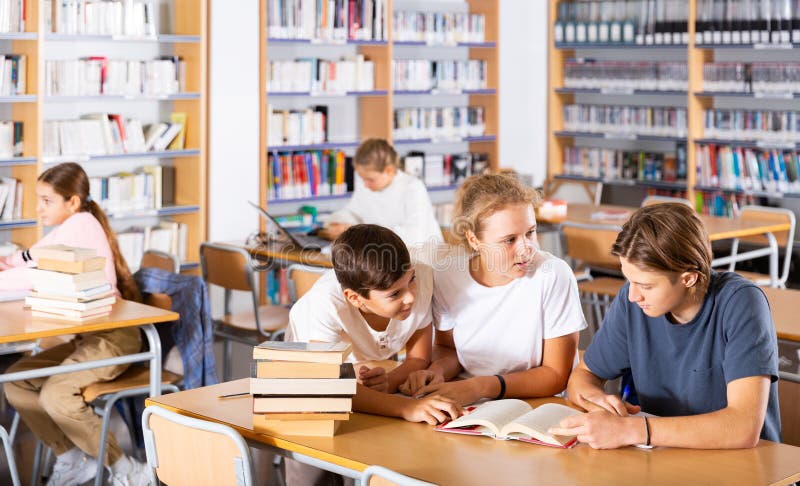 Three schoolchildren writes synopsis in an exercise book from the textbook