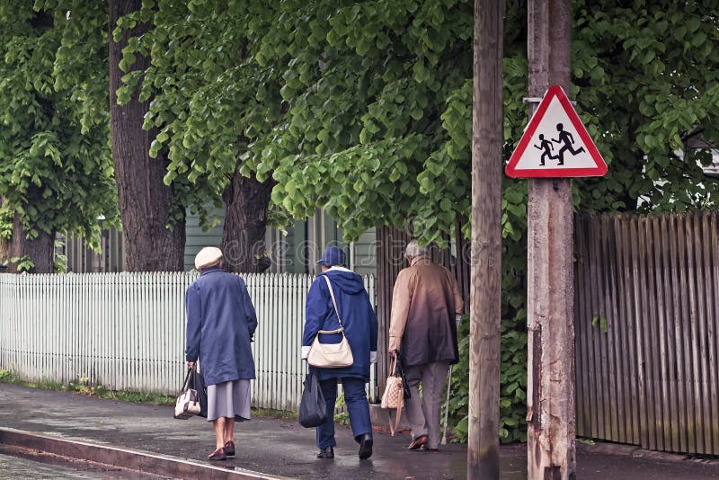 Three Seniors Walking Back From The Shops. Three grandmothers walking on a street on a rainy spring day at Tallinn, the capital of Estonia. The traffic sign royalty free stock photography Three Seniors Walking Back From The Shops. Three grandmothers walking on a street on a rainy spring day at Tallinn, the capital of Estonia. The traffic sign royalty free stock photography
