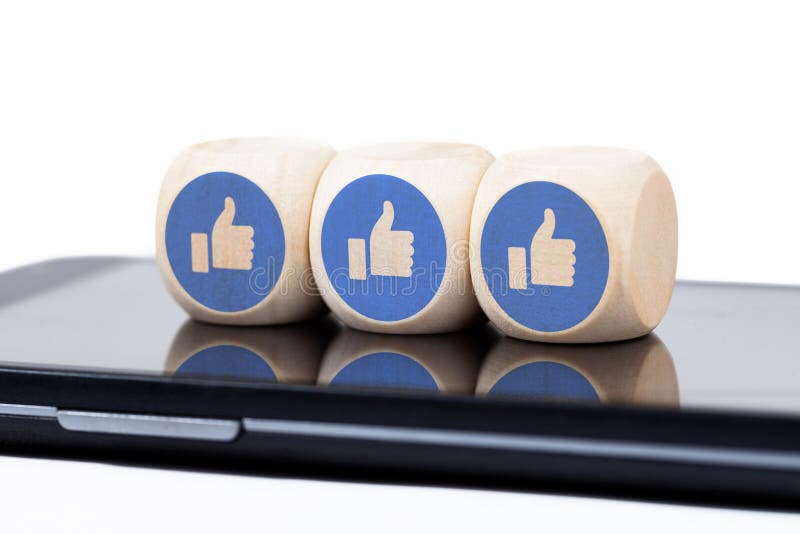 Three simple dice with Facebook like icons laying on a modern smartphone screen. Social media engagement concept