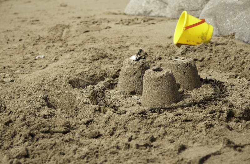 Three Simple Sandcastles with Yellow Bucket Stock Photo Image of