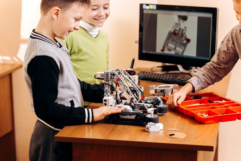 Three smart boys are making robots from the robotic constructor at the desk with computer in the School of Robotics royalty free stock photos Three smart boys are making robots from the robotic constructor at the desk with computer in the School of Robotics royalty free stock photos