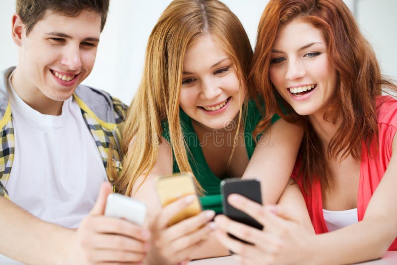 Three smiling students with smartphone at school royalty free stock photos Three smiling students with smartphone at school royalty free stock photos