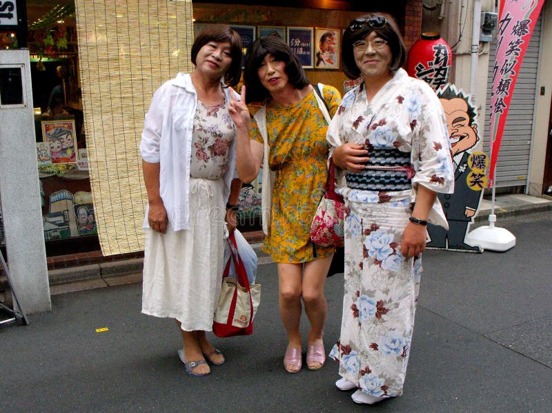 Three smiling transsexuals pose on a street in Tokyo stock images