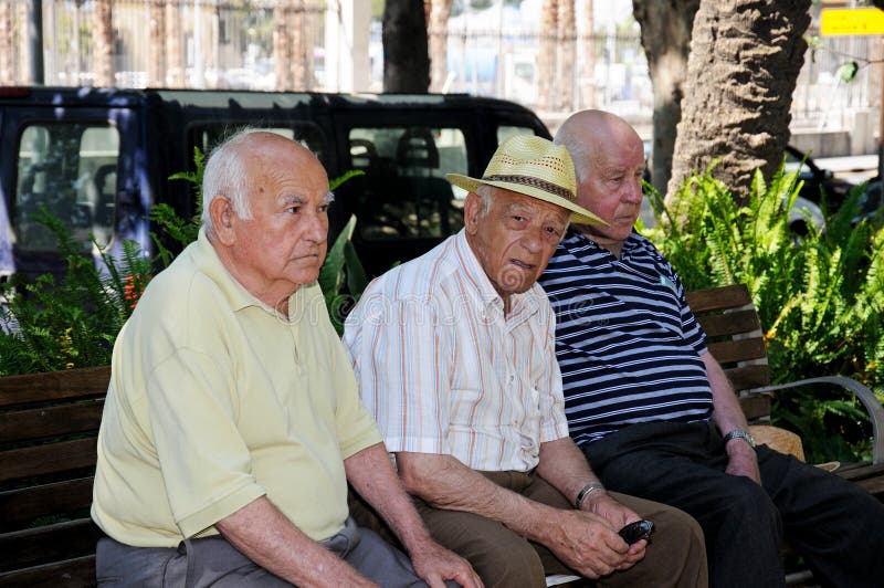 Three Spanish men sitting on bench.