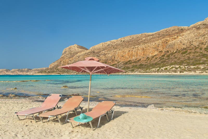 Three sunbeds, hat and umbrella on beach