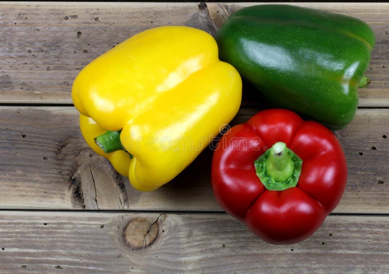 Three sweet peppers, wooden table background stock photos