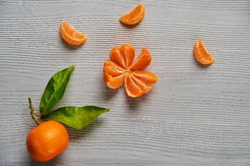 Three tangerine orange slices on the gray wooden board with free copy space. Fresh raw mandarin orange with green leaves