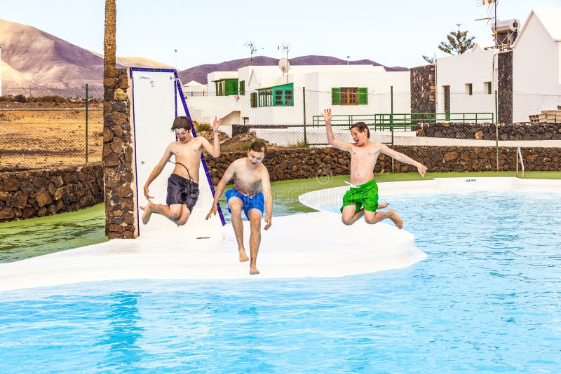 Three teen boys jumping in the pool