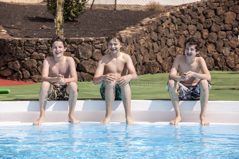 Three teen boys sitting at a pool