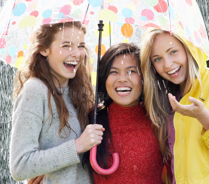 Three Teenage Girl Sheltering From Rain Beneath Umbrella