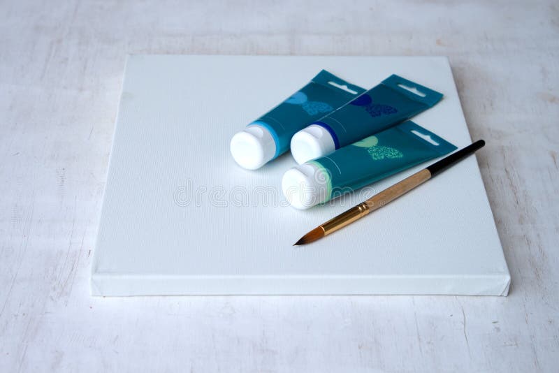 Three tubes of acrylic paint and a brush on white canvas. The set of the artist. stock images Three tubes of acrylic paint and a brush on white canvas. The set of the artist. stock images