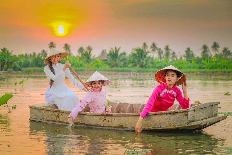 Three Vietnamese girls are rowing in the lotus garden