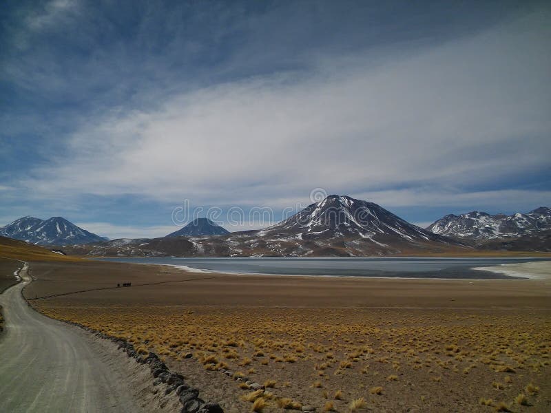 Tre vulcani in sequenza e una laguna blu sopra di esso, e la gente a piedi in un sentiero verso.