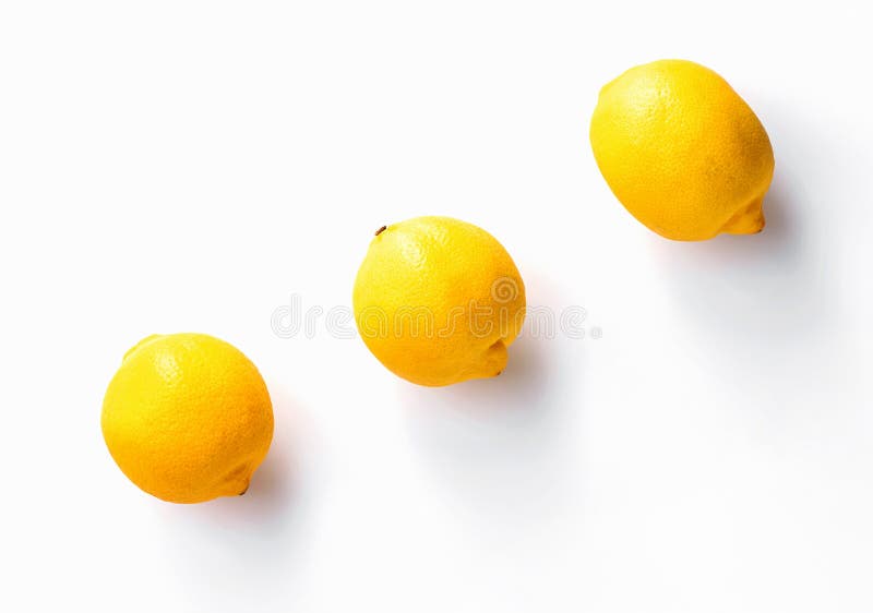 Three whole lemons diagonally on white background royalty free stock photo.