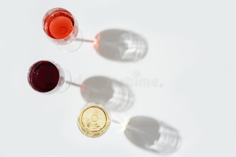 Three wine glasses top view.  Red, rose and white wine on light background with dark shadow. Three wine glasses top view.  Red, rose and white wine on light background with dark shadow