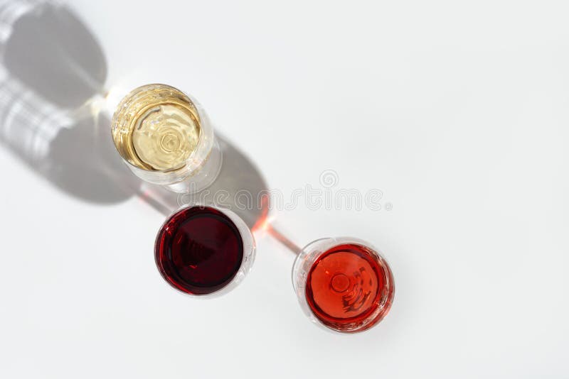 Three wine glasses top view.  Red, rose and white wine on light background with dark shadow. Three wine glasses top view.  Red, rose and white wine on light background with dark shadow