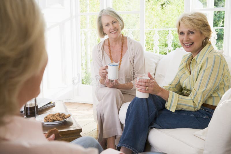 Tre donne in soggiorno con caffè sorridente.