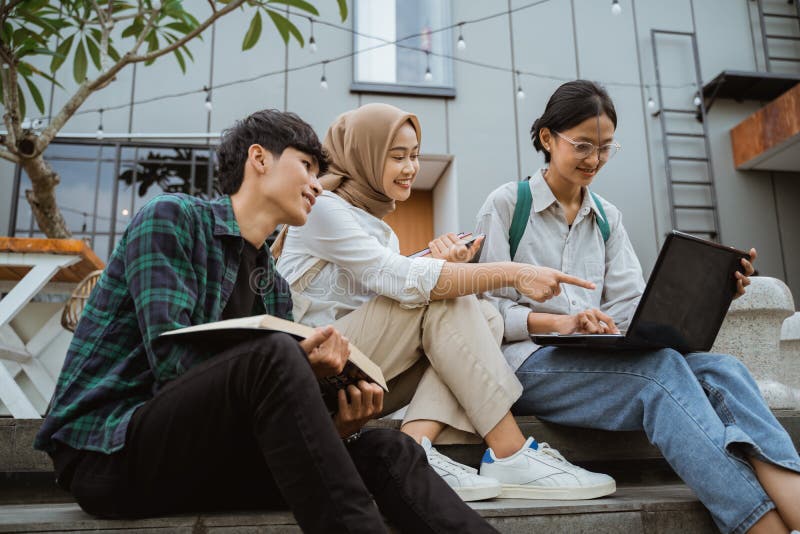 Three Young Asian College Students Using Laptops Sitting on Steps Stock