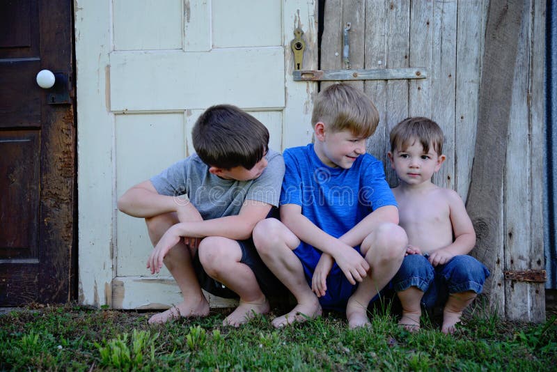 Three boys sitting against old weathered doors stock images Three boys sitting against old weathered doors stock images