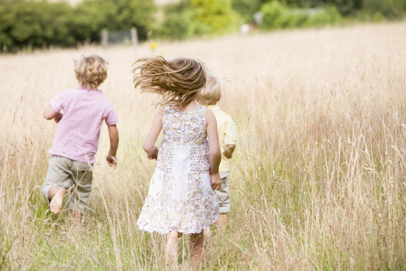 Three young children running outdoors from the back