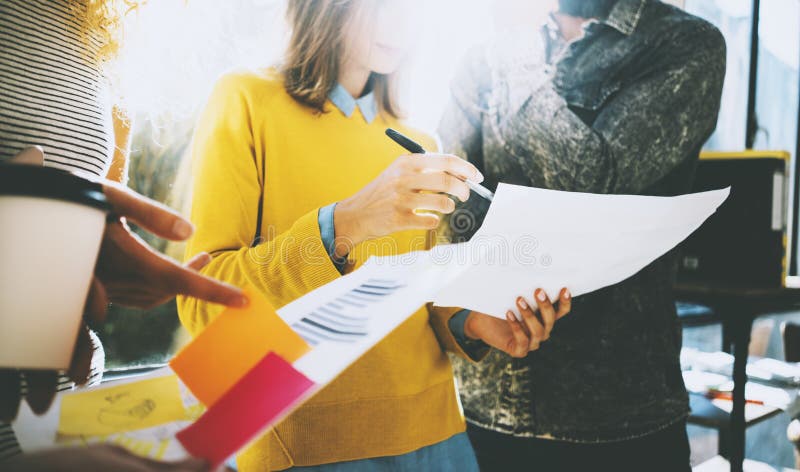 Three young colleagues discussing business strategy.Woman holding papers in her hands and showing document near the stock image Three young colleagues discussing business strategy.Woman holding papers in her hands and showing document near the stock image
