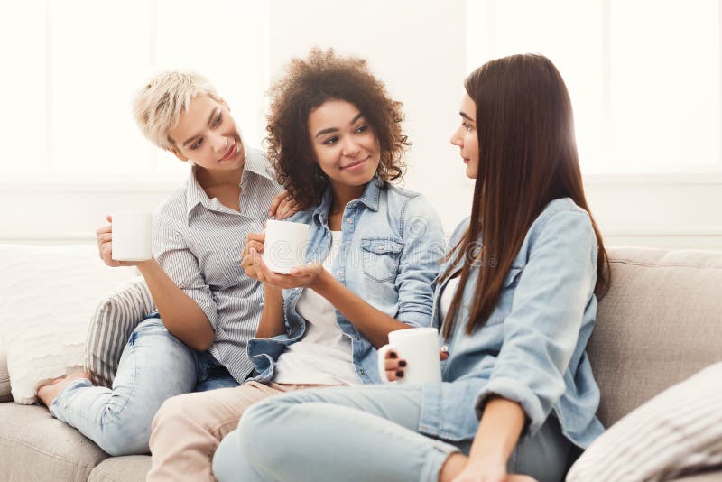 Three young female friends with coffee conversing