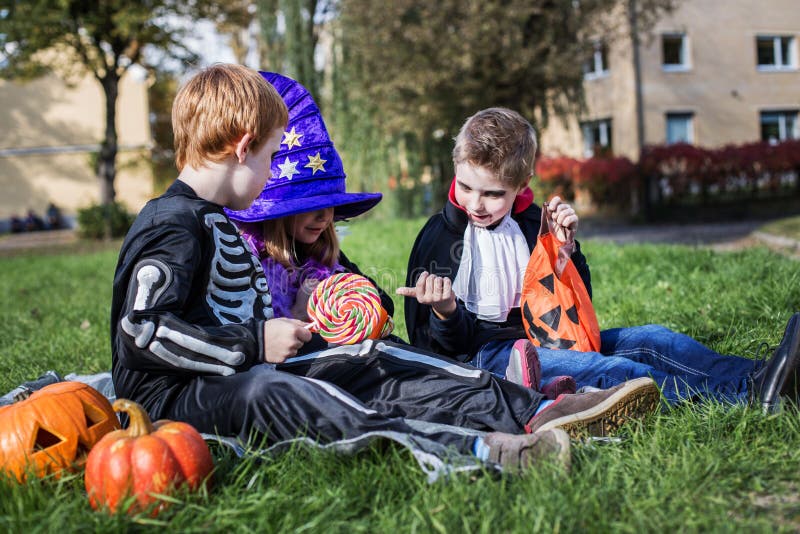 Three young friends sharing Halloween candies