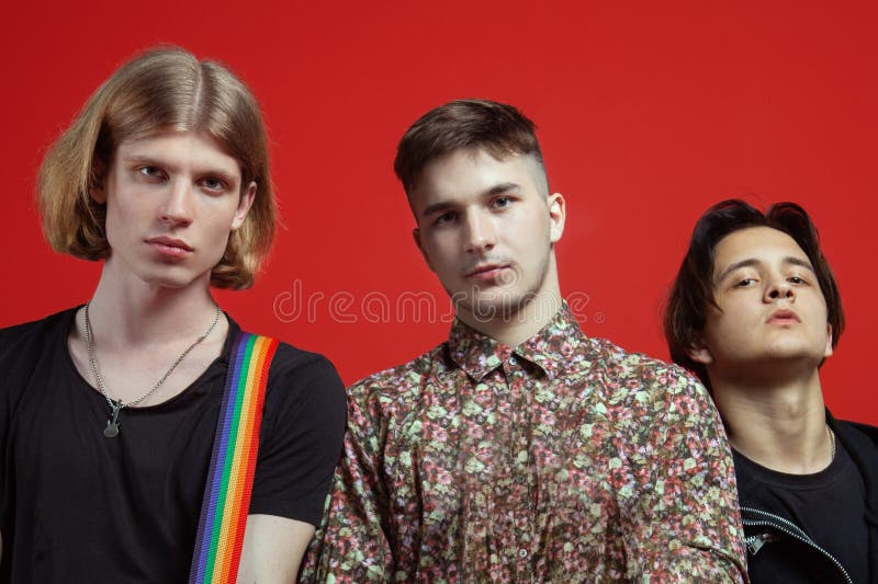Three young handsome men of different nationalities stand on vibrant red background. stock photography