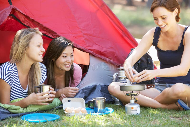Three Young Women Cooking On Camping Stove Outside Tent royalty free stock image Three Young Women Cooking On Camping Stove Outside Tent royalty free stock image