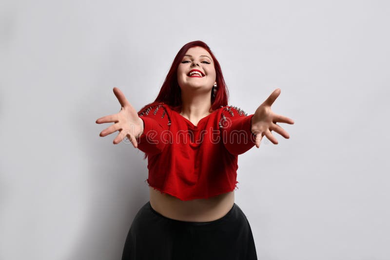 Overweight ginger girl in red headband, black top, leggings, sneakers.  Showing stop sign by her palm, posing on blue background Stock Photo