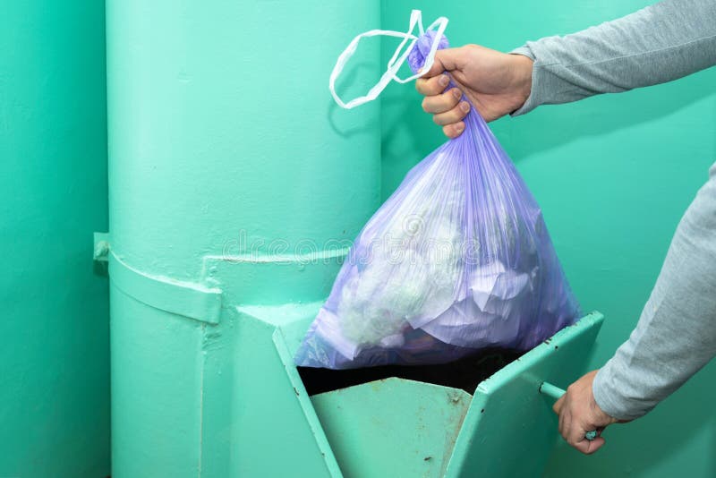 Throwing Garbage into the Garbage Chute, a Man`s Hand with a Garbage