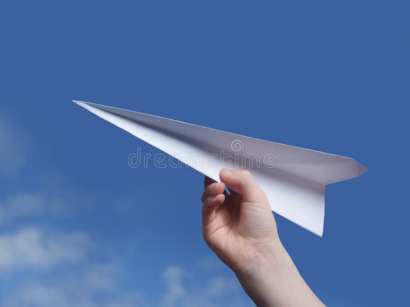 Childs hand throwing a paper plane..blue sky in background