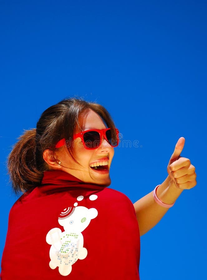 Back view of a beautiful caucasian young woman with sunglasses and Dreamstime shirt looking over her shoulder and showing her thumb up. Back view of a beautiful caucasian young woman with sunglasses and Dreamstime shirt looking over her shoulder and showing her thumb up